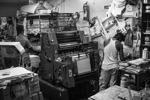 An ageing printing machine in a small Indian shop, showing visible wear and tear.