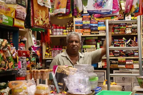 An Indian shopkeeper reviewing account books or a ledger at their shop