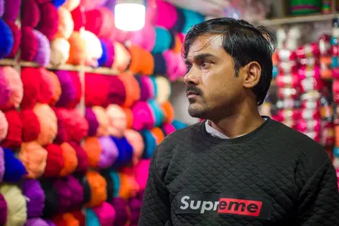 A shop owner standing behind a counter filled with notebooks and pens