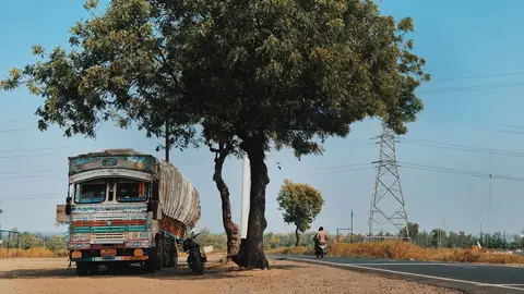 A wide, well-maintained four-lane Indian national highway stretching into the distance