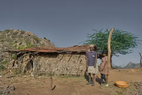 A family in a rural Indian village sitting outside a modest mud home
