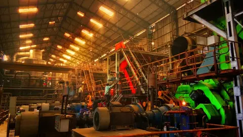 Workers operating heavy machinery inside an Indian factory.