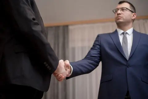 Two partners at a table discussing financial settlement, representing solvent partners covering a shortfall