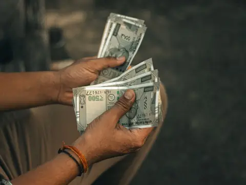 A person at a bank counter handing over cash, representing a partner topping up their capital contribution.