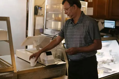A customer collecting a printed receipt at a shop counter in India