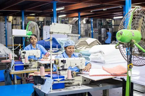 Workers operating sewing machines inside a textile factory in India