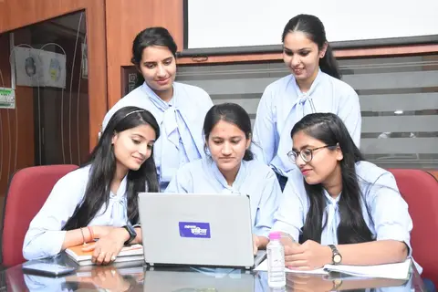 Indian office team collaborating around a table with a shared plan visible