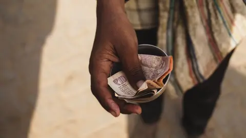 A farmer using a mobile phone to check a government direct benefit transfer, illustrating expansionary fiscal policy.