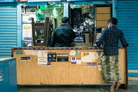 Indian shop owner at a billing counter representing everyday business expenses and assets