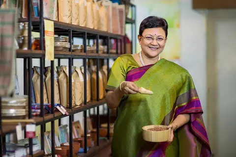 A kirana shop owner reviewing a notebook of daily sales records at the counter