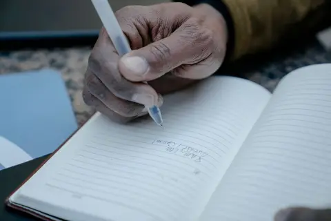 A business owner writing a corrective journal entry in a notebook