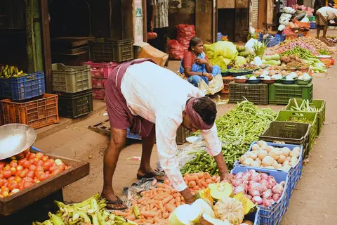 Busy Indian street market with small vendors selling daily goods to customers