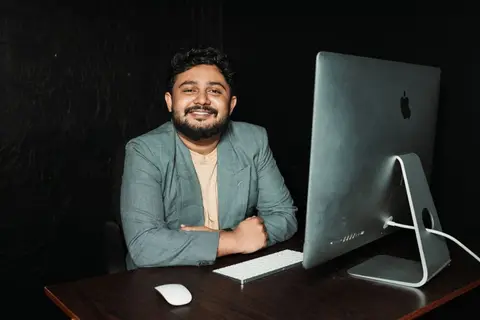 Two young Indian entrepreneurs working on laptops in a bright co-working space