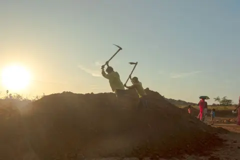 Rural workers in India digging a canal or earthwork under the MGNREGA employment guarantee scheme.