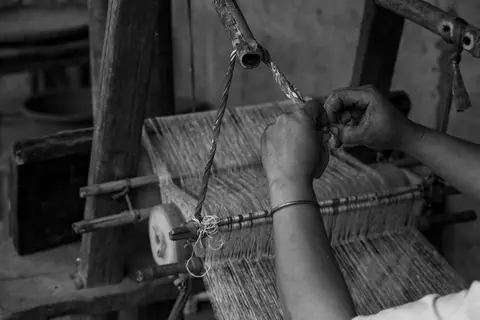 A traditional Indian handloom weaver at work on a wooden loom