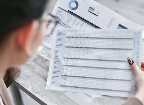 A finance professional reviewing audit reports and documents in a modern office.